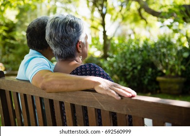 Rear View Of Senior Couple Sitting In Garden On A Sunny Day