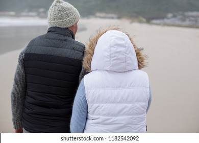 Rear View Of Senior Couple Walking Together On The Beach