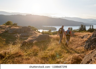 Rear View Of Senior Couple Walking On Top Of Hill On Hike Through Countryside In Lake District UK