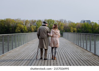 Rear view of senior man with daughter outdoors on a walk on pier by river. - Powered by Shutterstock