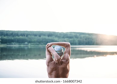 Rear View Of Senior Man Standing By Lake Outdoors Before Swimming, Stretching.