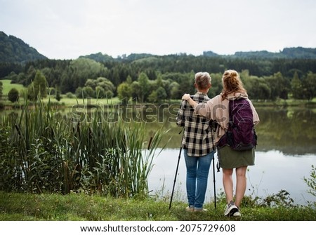 Similar – Foto Bild Rückansicht einer Frau mit rotem Hut, kurzer Jeans, Bluse und gemusterten Strümpfen steht auf einem großen Platz mit gemustertem Belag