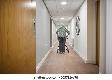 Rear View Of Senior Woman With Walker Walking Along Corridor In Retirement Home - Powered by Shutterstock