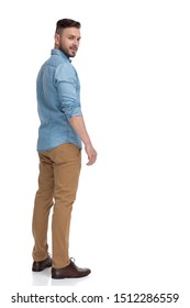 Rear View Of A Sexy Casual Man With Blue Shirt Standing And Looking Back Over Shoulder Cool On White Studio Background