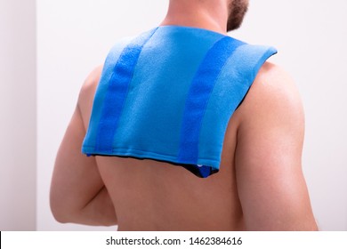 Rear View Of A Shirtless Man With Blue Ice Pack On His Shoulders And Back