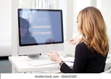 Rear View Shoot Of Businesswoman Sitting At Her Computer While Log In And Typing Password To Checking Her Bank Account. 