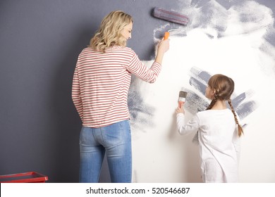 Rear View Shot Of A Casual Woman And Her Cute Daughter Painting The Wall Together In The Living Room.