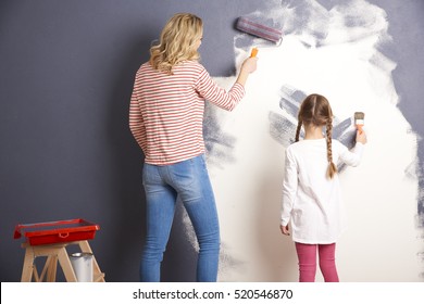 Rear View Shot Of A Casual Woman And Her Cute Daughter Painting The Wall Together In The Living Room.