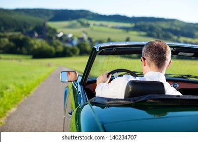 Rear View Shot Of Man Driving A Convertible Car Outdoors