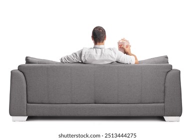 Rear view shot of a man sitting on a sofa and eating popcorn isolated on white background