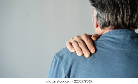 Rear view shot of a man suffering from a shoulder pain - Shutterstock ID 2238579365