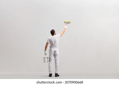 Rear view shot of a painter holding a bucket and painting a wall isolated on white background - Shutterstock ID 2070900668