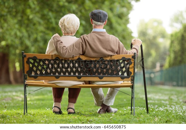 公園の木のベンチに座っている老夫婦の後方の写真 の写真素材 今すぐ編集