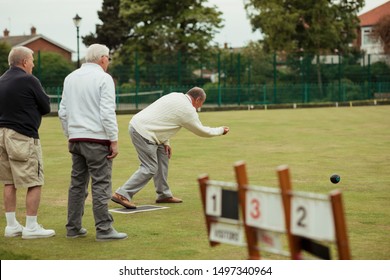 A rear view shot of a senior man taking his shot in a game of lawn bowling.