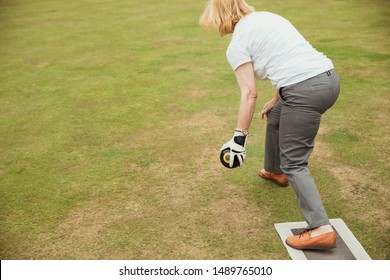 A Rear View Shot Of A Senior Woman Holding A Bocce Ball, Ready To Take Her Shot In A Lawn Bowling Game.