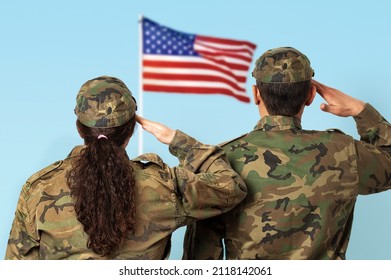 Rear view shot of two US soldiers saluting the US flag.