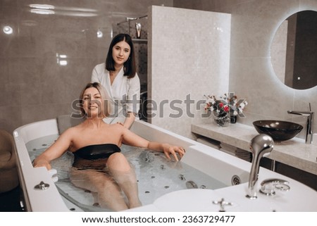 Rear view shot of a woman enjoying hydromassage in whirl pool bath. Relaxed woman getting hydromassage from professional beautician at spa center. High quality photo