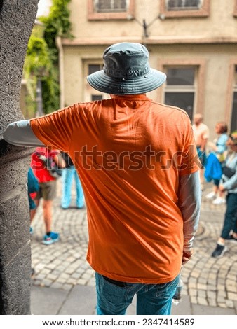 Rear view of a single mature man standing in an arched doorway with his arm resting on the stone structure. He is a tourist in the city of Koblenz, Germany.