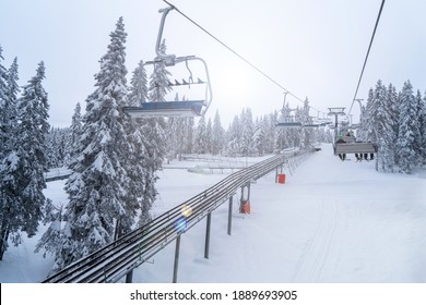 Rear View Of Skiers Riding The Cable Car. Bob Sled On Rails Under The Skiers On The Cable Car