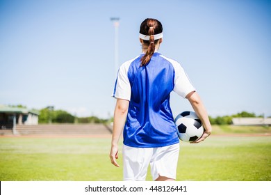 Rear view of soccer player standing in stadium with a ball