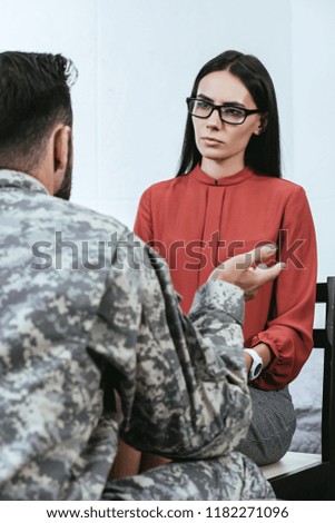 rear view of soldier talking at psychiatrist and gesturing during therapy session
