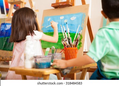 Rear View Of Some Kids Working On A Painting And Drawing Some Clouds For Art Class