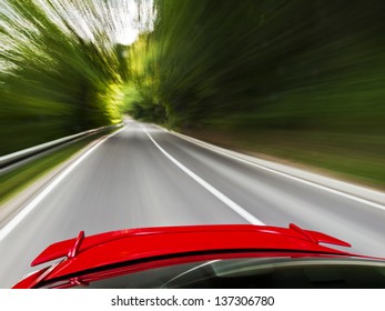 Rear View Of A Sports Car Driving Fast On A Winding Road In The Woods