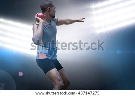 Rear view of sportsman practising shot put against spotlights