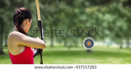 Rear view of sportswoman doing archery on a white background against park on sunny day
