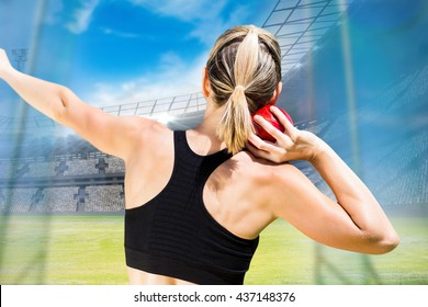 Rear view of sportswoman is practising shot put against view of a stadium - Powered by Shutterstock