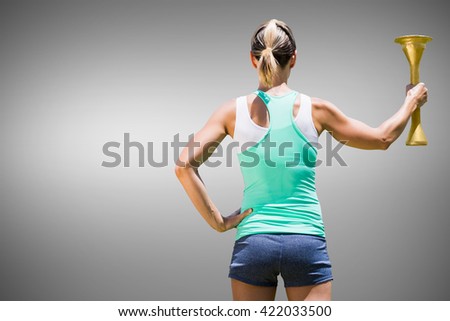 Rear view of sporty woman holding Olympic torch against grey background