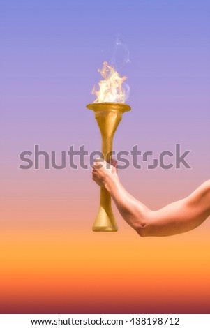 Rear view of sporty woman holding Olympic torch against sunrise sky