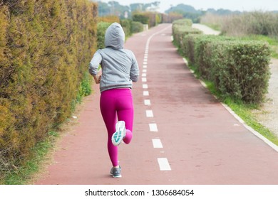 Rear view of sporty woman in pink leggings running over track in park. Lady training outdoors. Sport lifestyle concept - Powered by Shutterstock