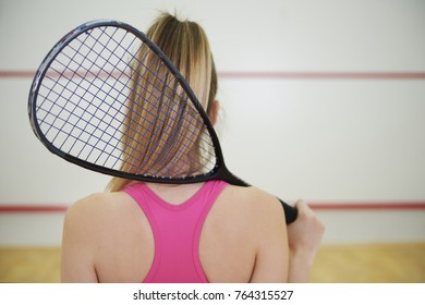 Rear view of squash or tennis player with racket 