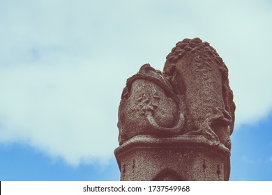 A rear view of a statue of two lions on a pedestal against a cloudy blue sky background in Bruges, Belgium