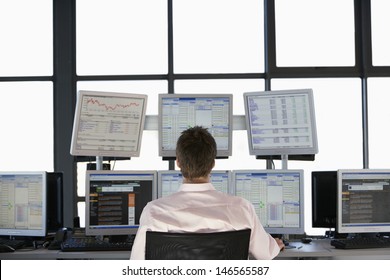 Rear View Of Stock Trader Looking At Multiple Computer Screens