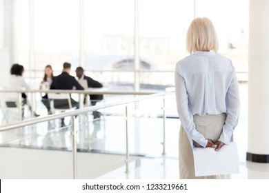 Rear view at stressed nervous middle aged senior old business woman applicant waits for job interview holding papers behind back preparing for performance feel afraid of public speaking fear concept - Powered by Shutterstock