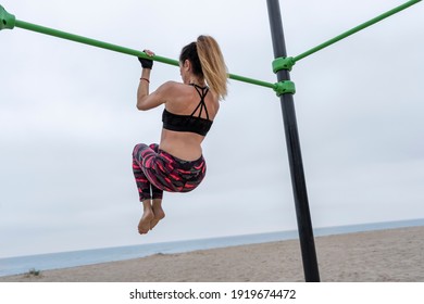 Rear View Of Strong Fit Female Doing Pull Up Exercise In Gym Bars On Beach.Athletic Sportswoman During Workout In Calisthenics Street Outdoor Gym Bars