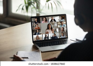 Rear view student wearing headphones engaged in online conference, using laptop, writing notes, sitting at desk, intern studying online, internet negotiations with diverse colleagues, online meeting - Shutterstock ID 1838627860