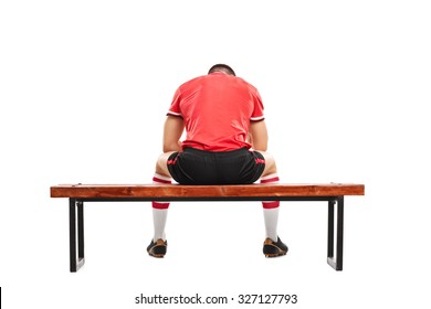 Rear view studio shot of a sad male football player sitting on a wooden bench and looking down isolated on white background - Powered by Shutterstock