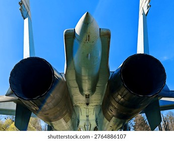 A rear view of the tail section of a Soviet Su-27 fighter jet, showing the two massive jet engine nozzles, the center boom, and the two vertical stabilizers.