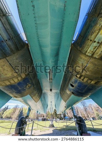 A rear view of the tail section of a Soviet Su-27 fighter jet, showing the two massive jet engine nozzles, the center boom, and the two vertical stabilizers.