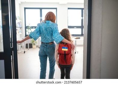Rear view of teacher with Ukrainian schoolgirl in classroom, concept of enrolling Ukrainian kids to schools. - Shutterstock ID 2137605657