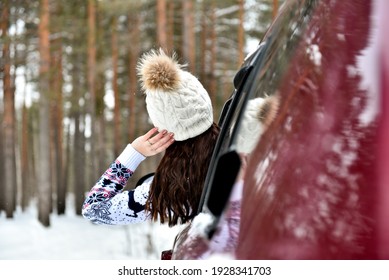 Rear View Of Teen Girl In Car Over Snowy Forest On Winter Roadtrip To The Nordic Way