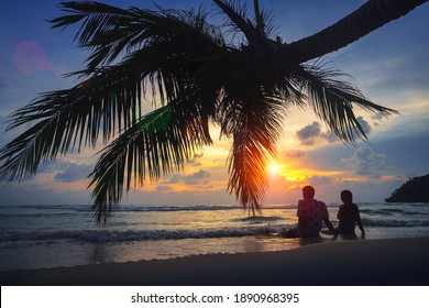 Rear View Of Teenage Couple Sitting On The Beach At Sunset, Koh Kut Thailand