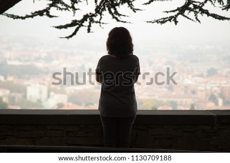 Rear view at thoughtful woman silhouette standing at view point looking at city watching urban cityscape vision pondering over question or problem, contemplating thinking of future loneliness concept