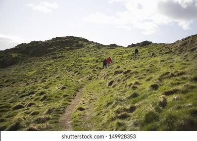 Rear view of three adults climbing up country hill