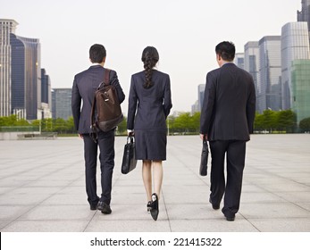 Rear View Of Three Business People Walking On Street.