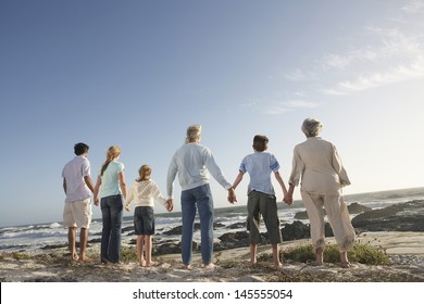 Rear View Of Three Generation Family Holding Hands On Seashore