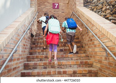 Rear View Of Three School Kids Climbing Brick Stairs On A Sunny Day